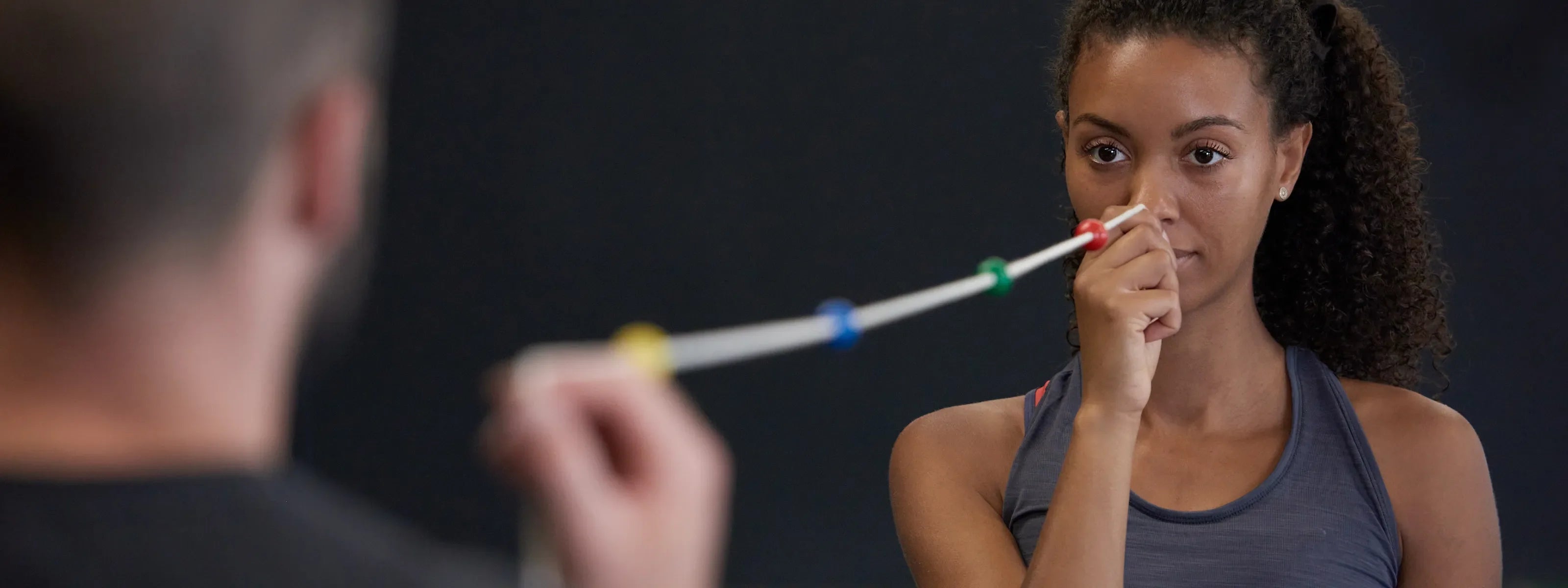 Frau hält sich einen ARTZT neuro Brock String an die Nasenspitze, dessen anderes Ende von einem Mann gehalten wird.