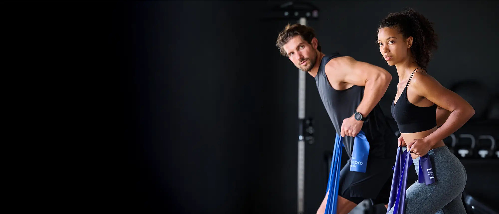 Ein Mann und eine Frau trainieren je mit einem ARTZT thepro Fitnessband, einem Klassiker der Fitnessgeräte.