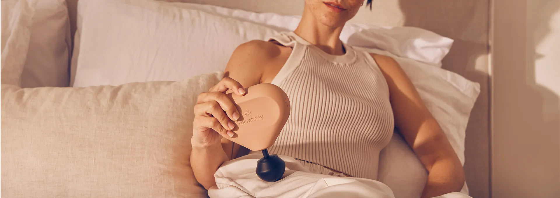 Frau behandelt ihren rechten Oberschenkel mit einer Theragun Mini Massagepistole.