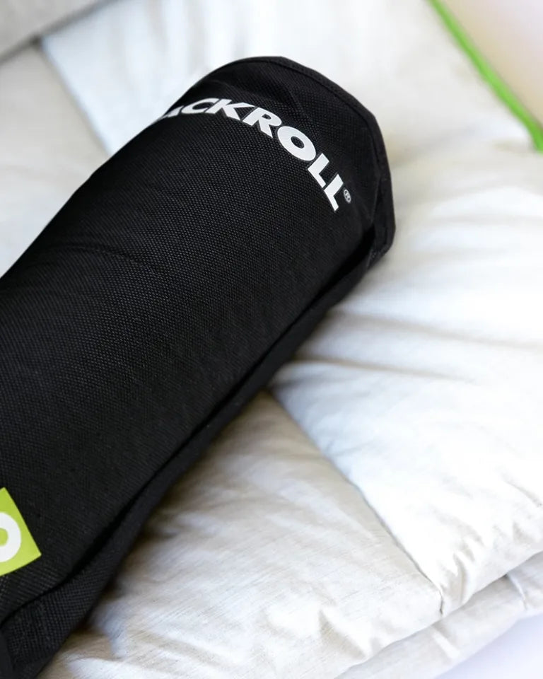 Die Tasche des BLACKROLL Recovery Pillow liegt auf einer weißen Decke.