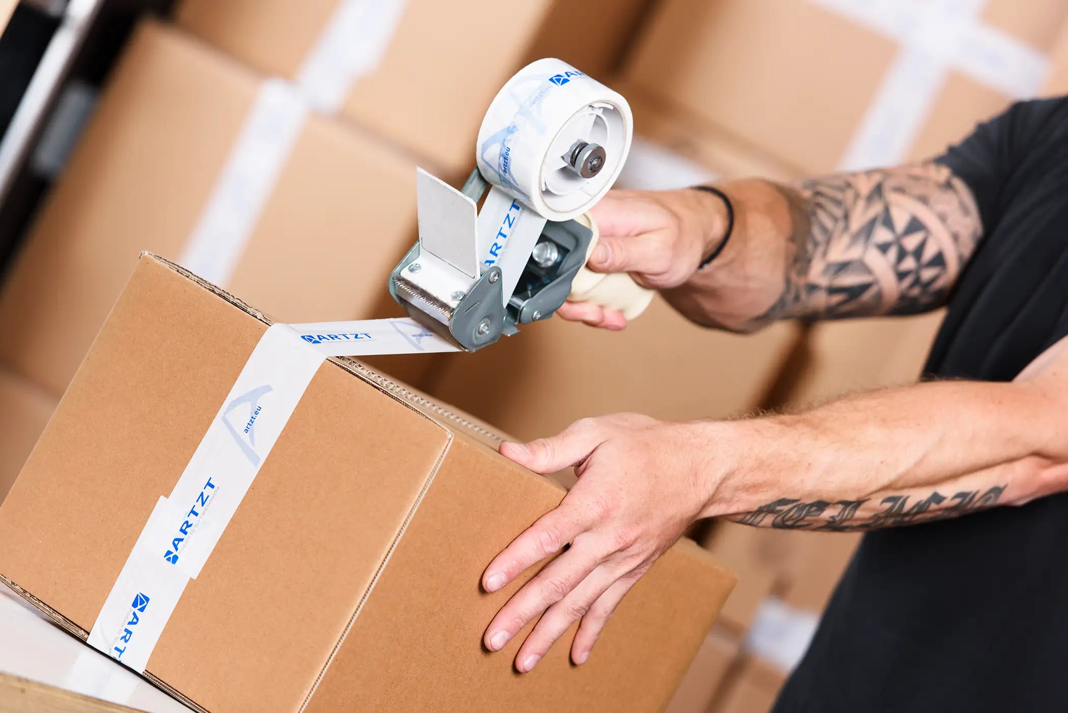 Ein Karton wird mit ARTZT-Paketband zugeklebt.