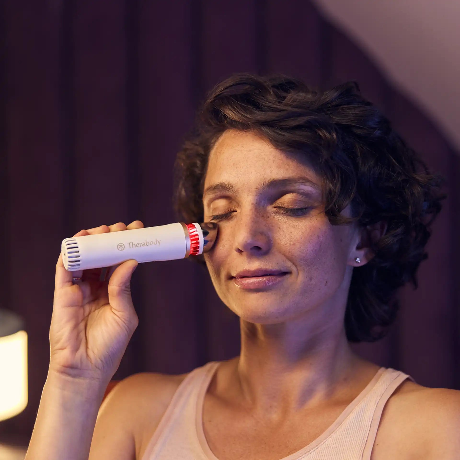 Frau wendet TheraFace Depuffing Wand zu Hause unter den Augen an