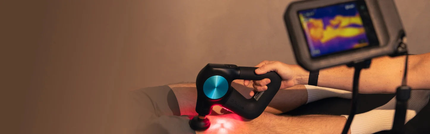 Eine Theragun Massagepistole wird in Nahaufnahme an eine Oberschenkelrückeite gehalten