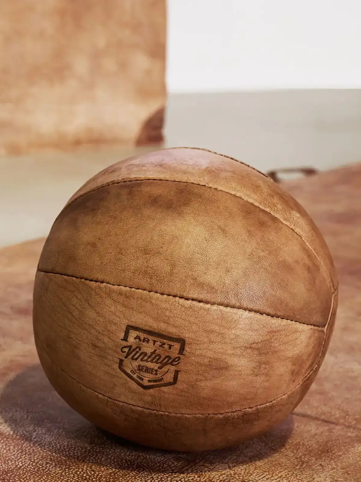 Ein ARTZT Vintage Series Leder Medizinball liegt auf einer Ledermatte.