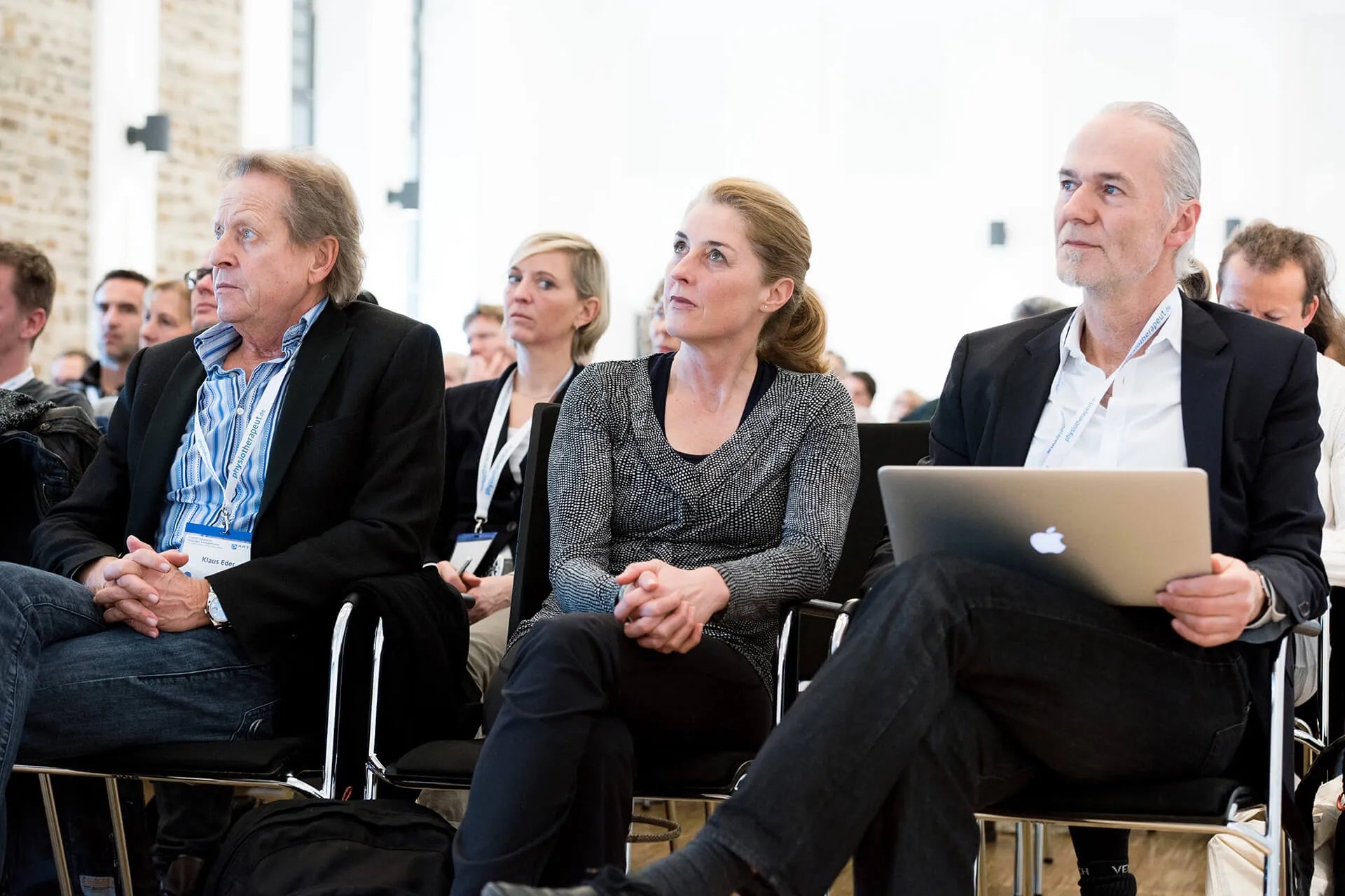 Mehrere Personen, darunter Ex-DFB-Physiotherapeut Klaus Eder und Faszienexperte Dr. Robert Schleip, sitzen auf Stühlen.