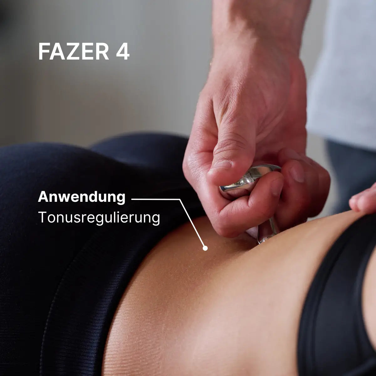 Therapeut verwendet den ARTZT thepro Fazer 4 am unteren Rücken einer liegenden Person zur Tonusregulierung; die Nahaufnahme zeigt das kompakte, präzise geführte Tool, das gezielt auf die Muskulatur wirkt.