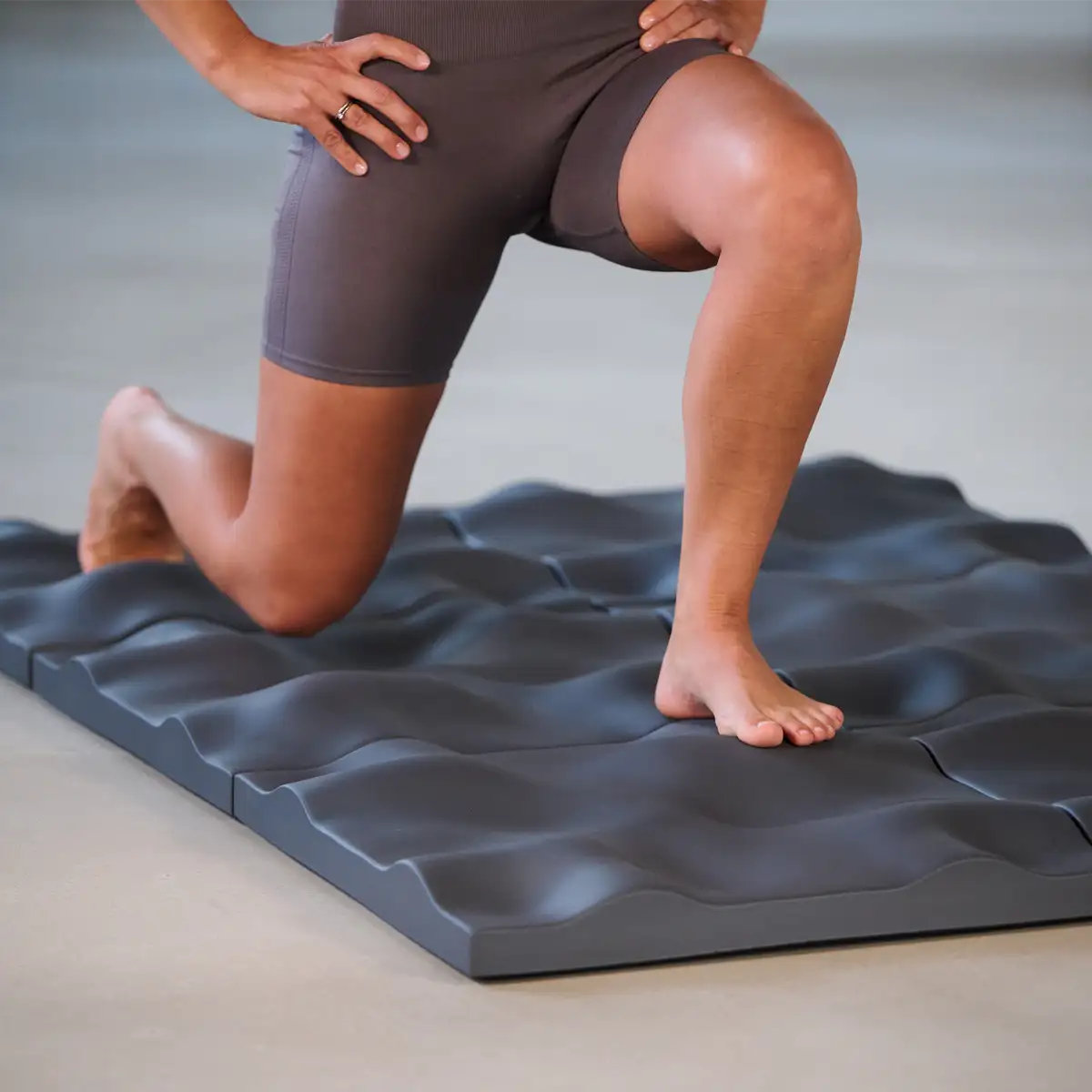 Person führt eine Ausfallschritt-Übung auf dem Sensorikboden der Marke ARTZT thepro aus; die wellenförmig strukturierte Oberfläche fördert Gleichgewicht, Tiefensensibilität und muskuläre Aktivierung im Fuß- und Beinbereich.