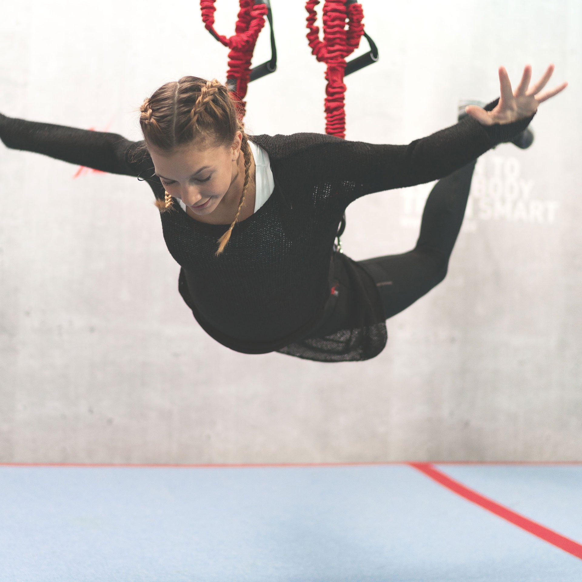 Eine Frau hängt Waagerecht auf Hüfthöhe in einem 4D PRO Schlingentrainer