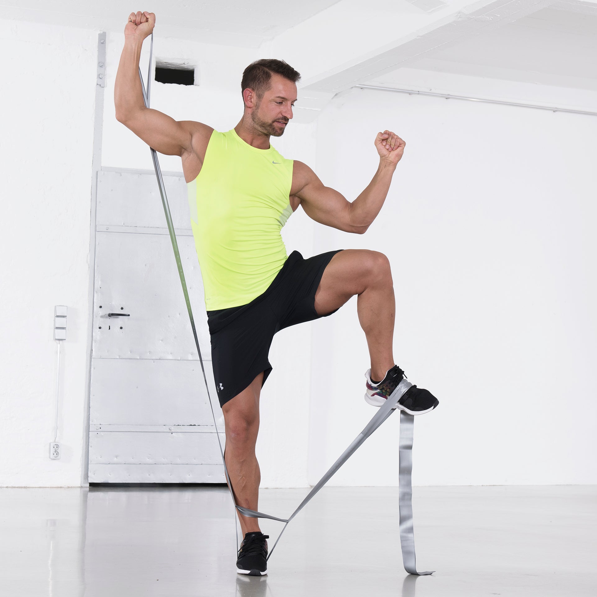 Mann macht Ganzkörpertraining mit einem silbernen TheraBand CLX