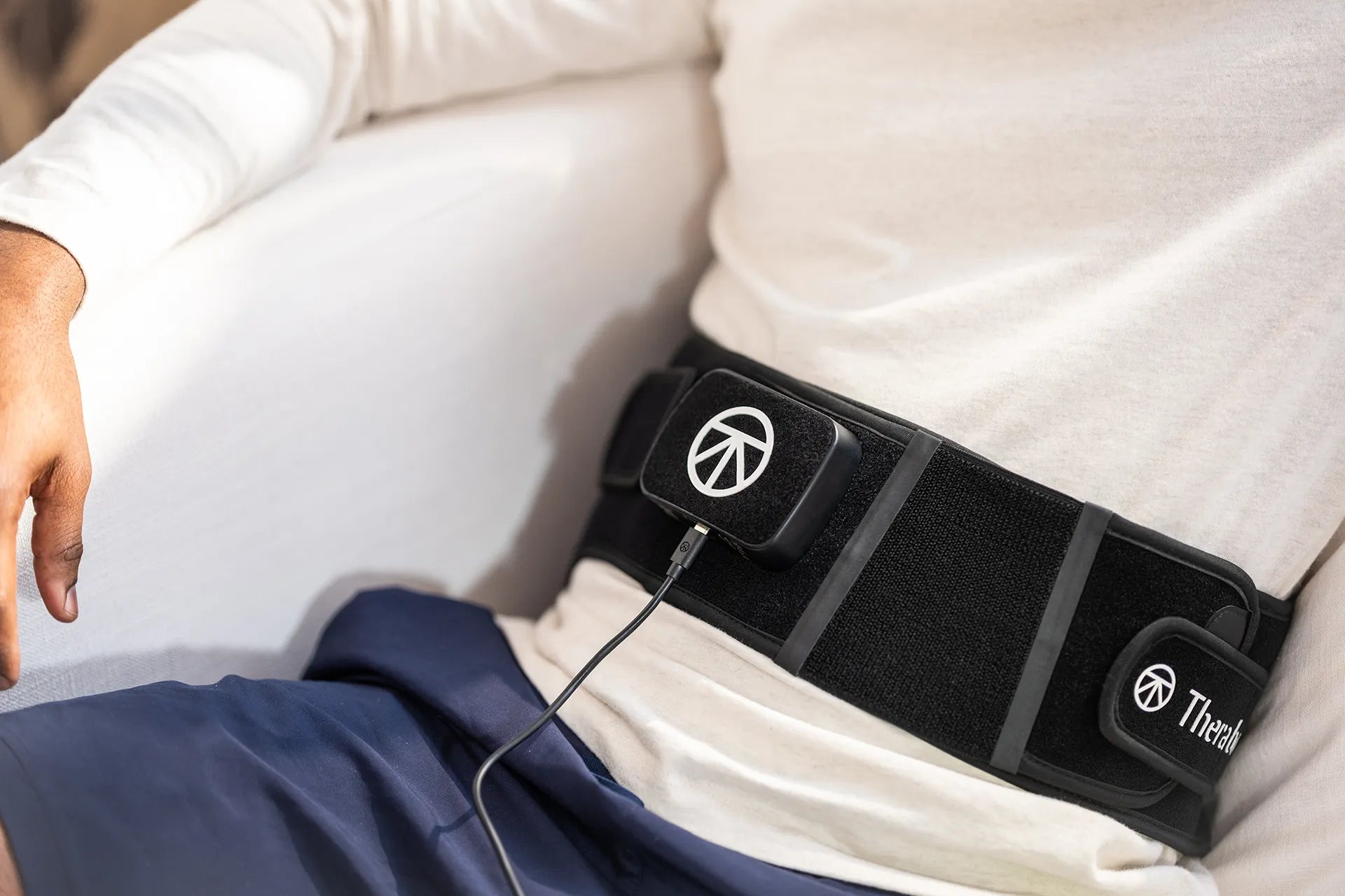 Nahaufnahme Therabody ThermBack LED mit angeschlossenem USB-Ladekabel.