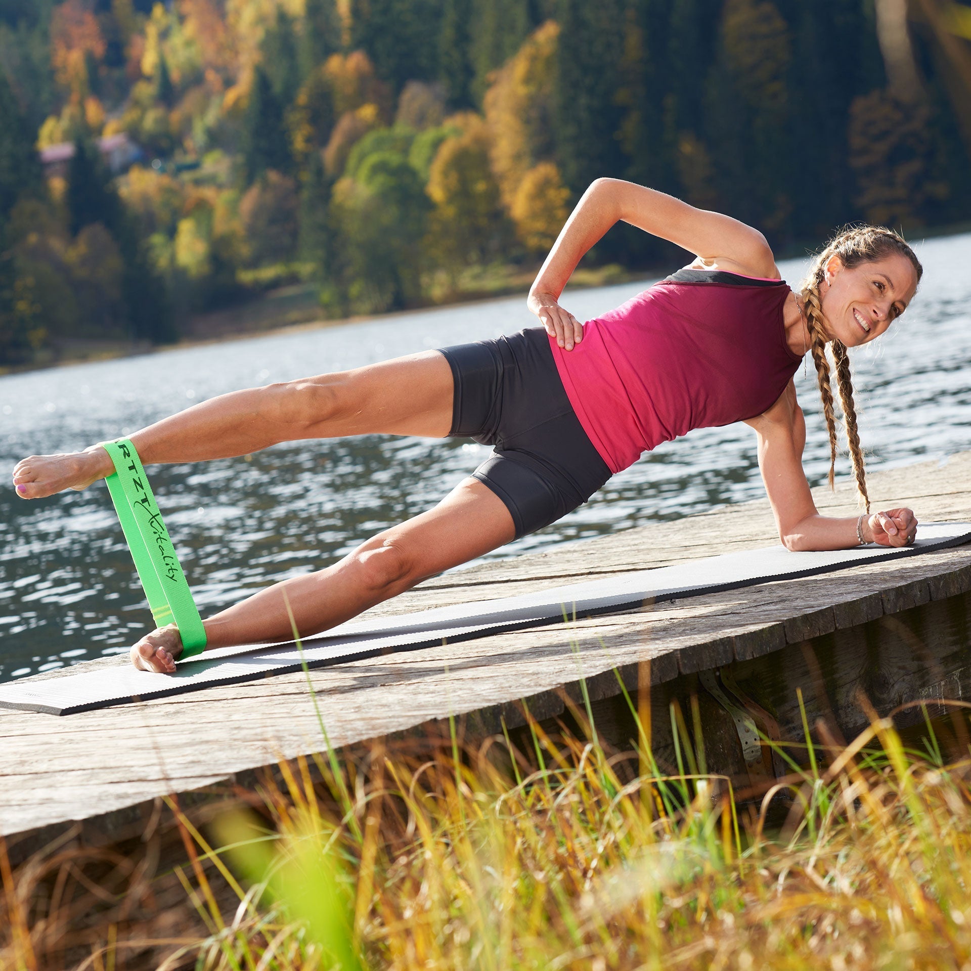 Frau trainiert im Seitstütz mit einem grünen Loop Band