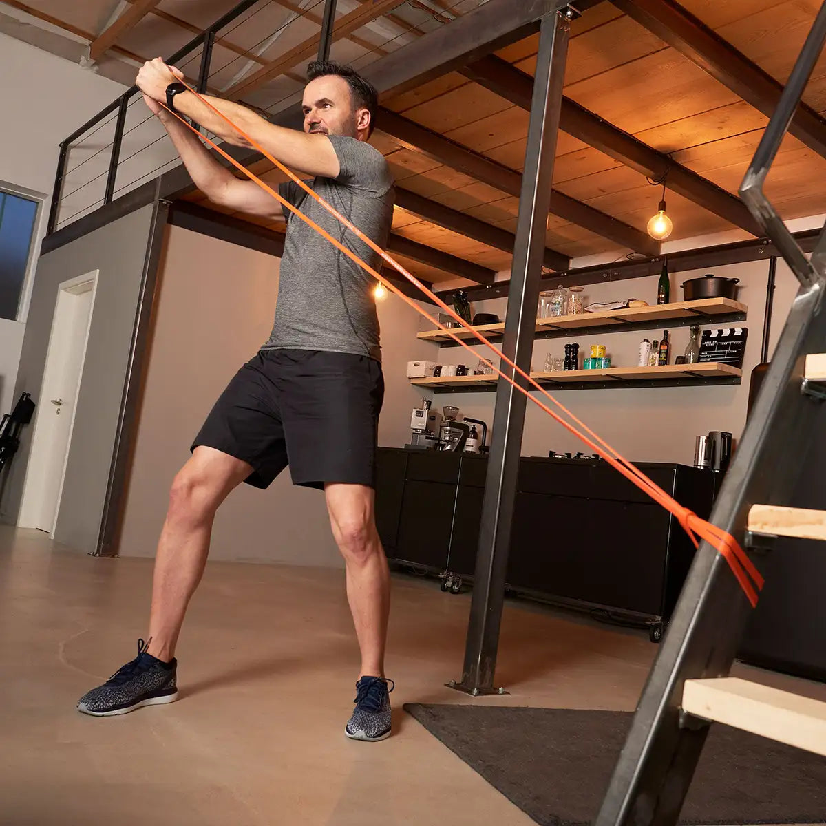 Mann trainiert mit rotem TheraBand High Resistance Band.