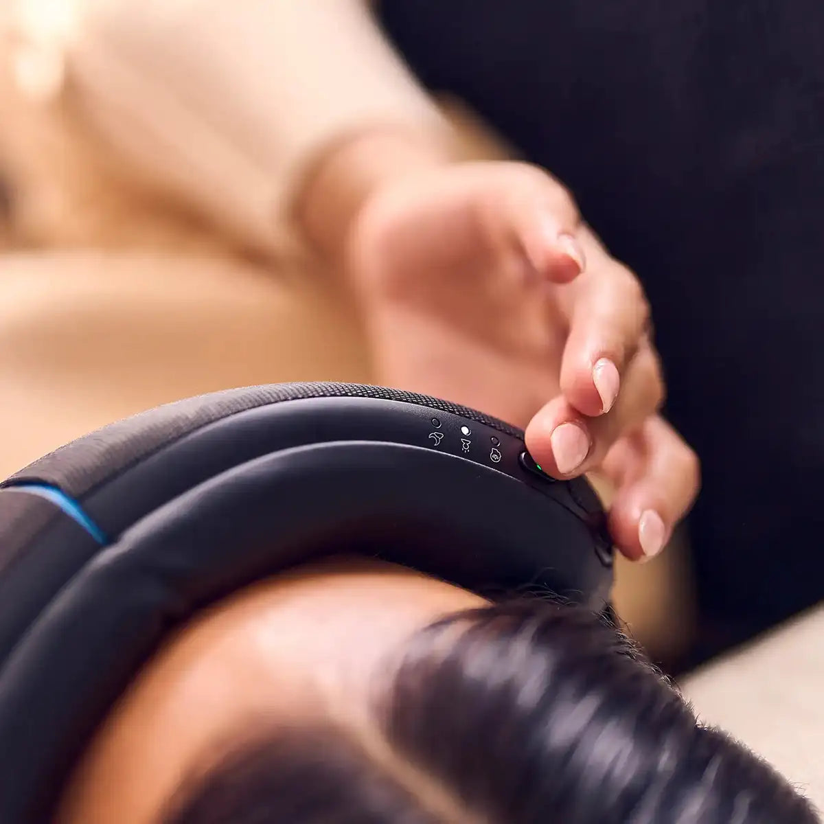 Nahaufnahme einer Frau, die mit der rechten Hand ein Therabody SmartGoggles Wearable bedient.