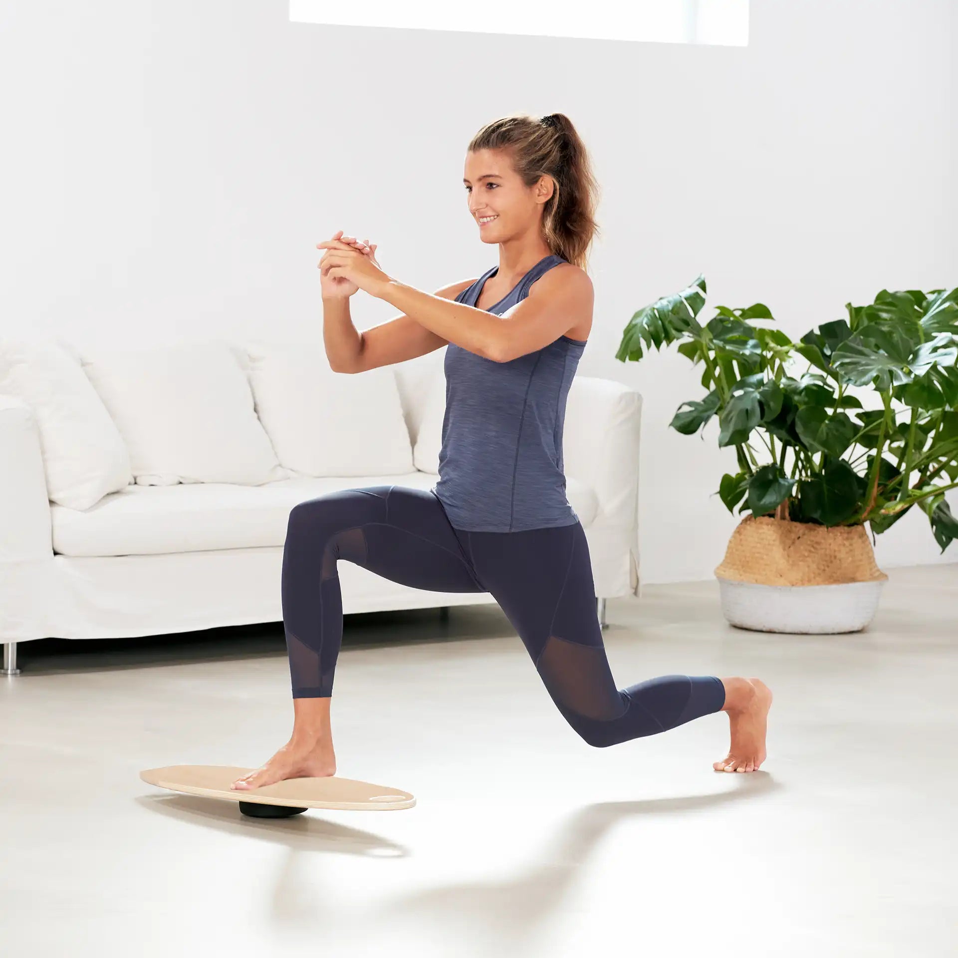Frau trainiert Gleichgewicht mit Wobblesmart XL Balance Trainer von ARTZT vitality im Wohnzimmer
