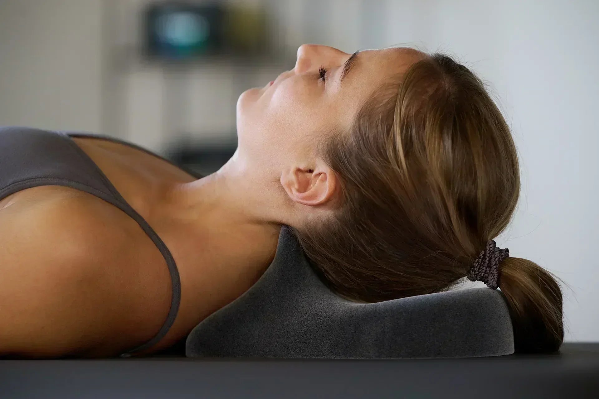 Frau liegt entspannt auf dem Rücken, der Nacken ruht auf dem ergonomischen Lagerungskissen Cranibas zur Entlastung bei Nackenschmerzen.