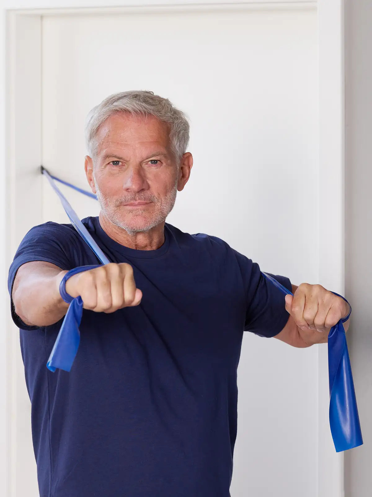 Mann trainiert mit einem blauen TheraBand mit Türanker