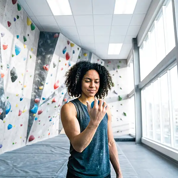 Frau trainiert die Griffkraft für Klettern mit TheraBand Theraputty in einer Boulder-Halle