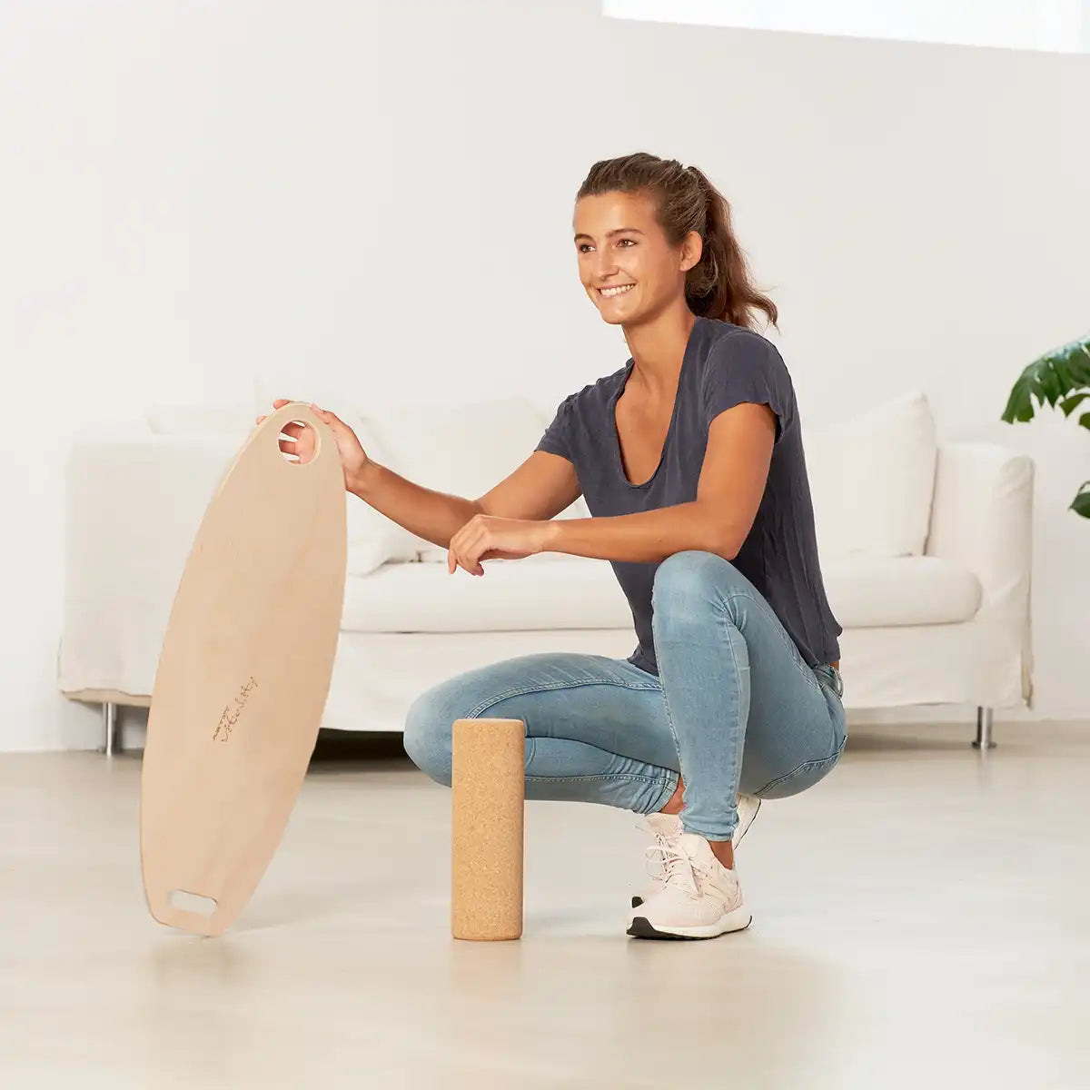 Frau hockt im Wohnzimmer mit Balance Board von ARTZT vitality