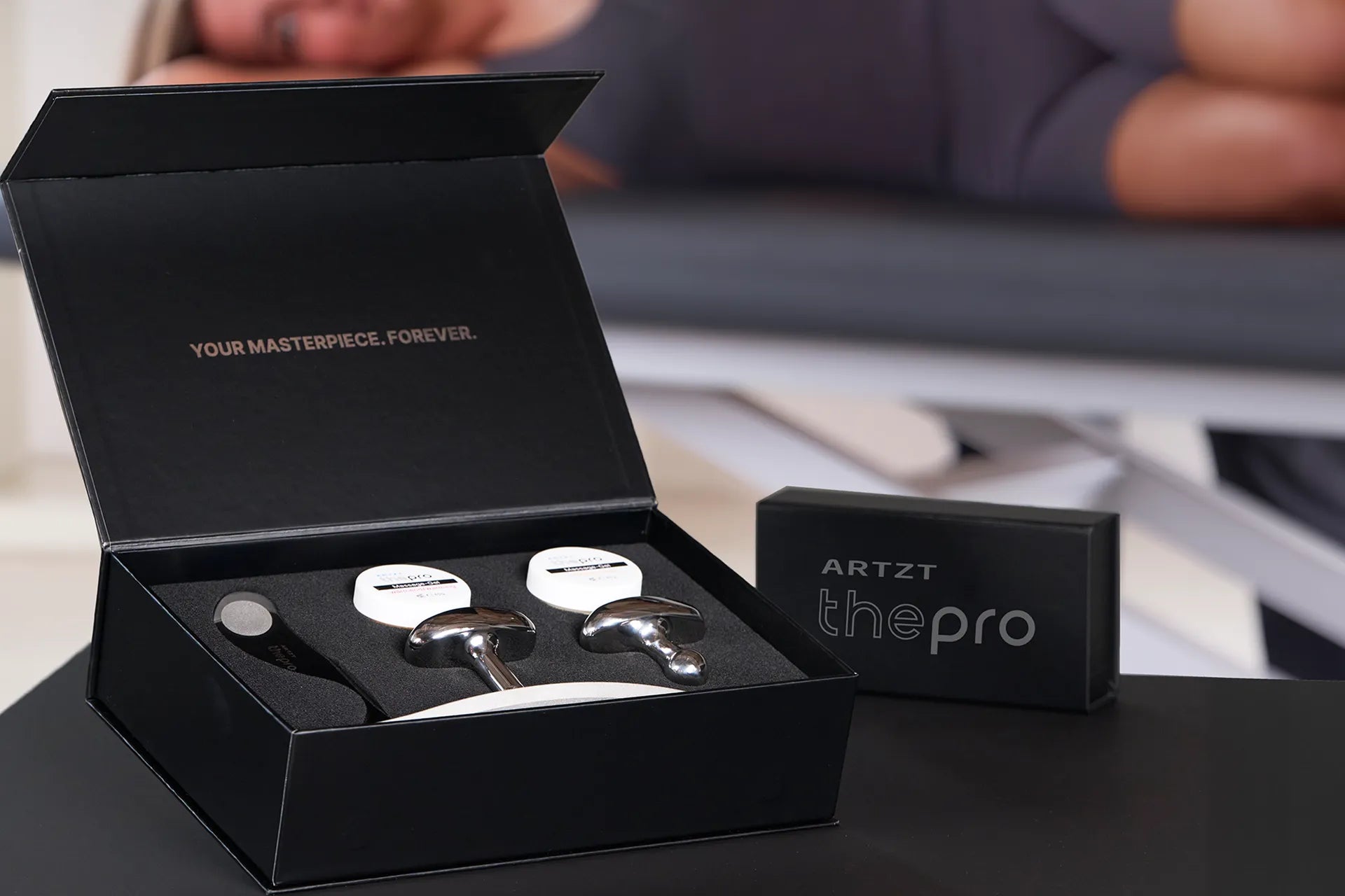 Geöffnete Produktverpackung des ARTZT thepro Fazer für Faszientherapie mit mehreren Edelstahl-Tools und Zubehör in schwarzer Box.