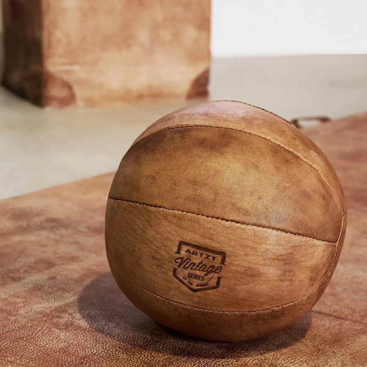 Ein ARTZT Vintage Series Medizinball liegt auf einer brauen Ledermatte.