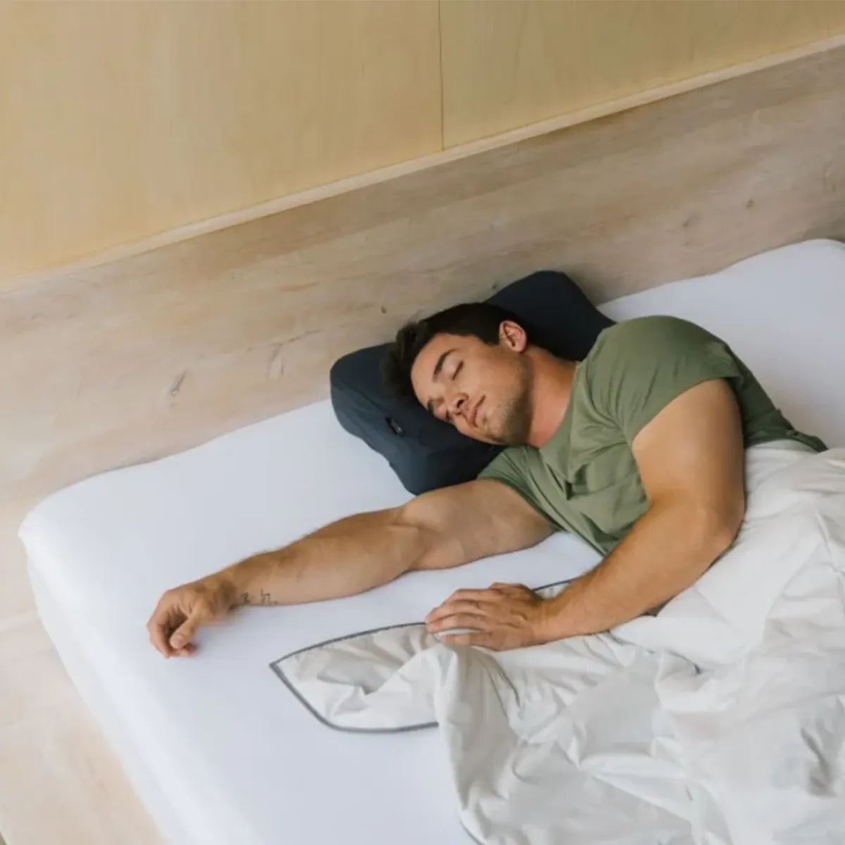 Mann liegt im Bett mit dem Kopf auf einem Blackroll Kissen mit Pillow Case in der Farbe Anthrazit.