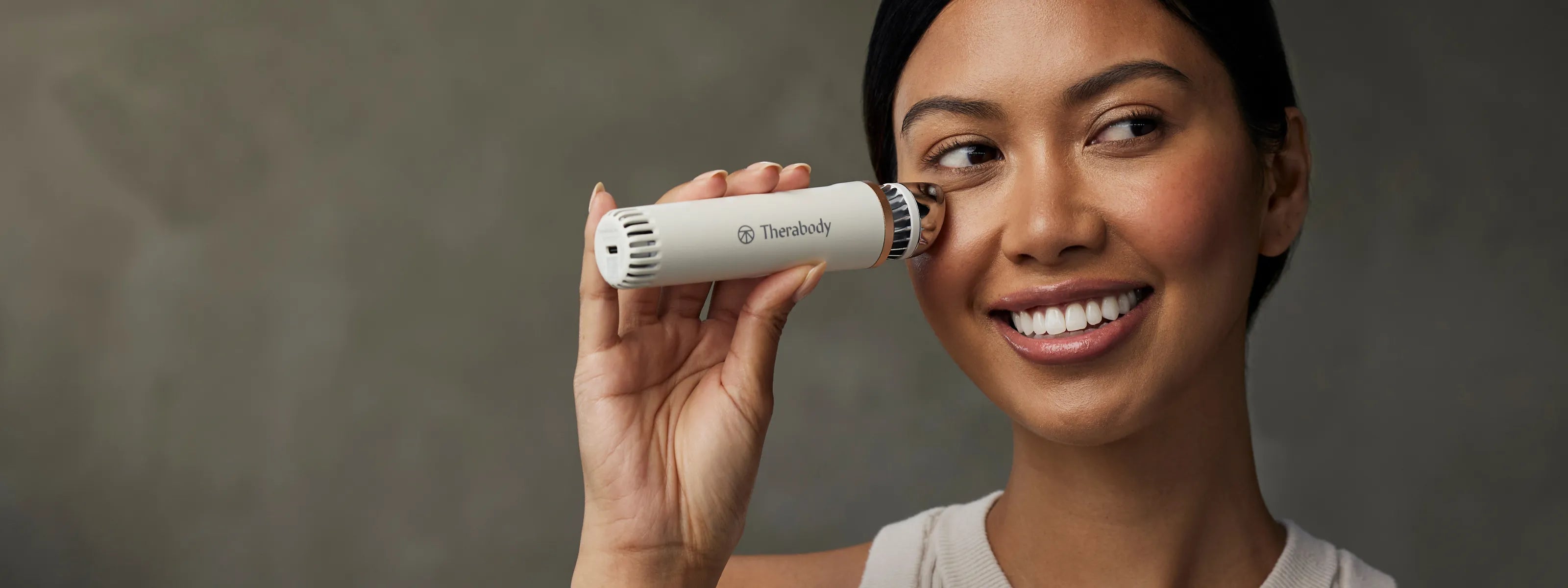 Frau hält sich den Therabody Depuffing Wand an die rechte Wange.