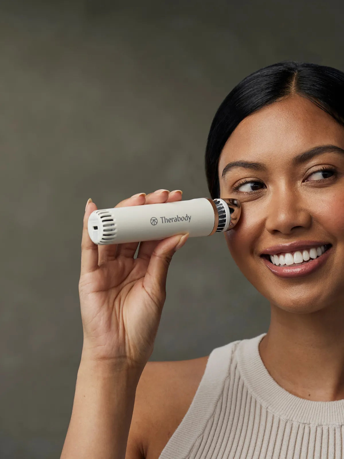 Frau hält sich den Therabody Depuffing Wand an die rechte Wange.