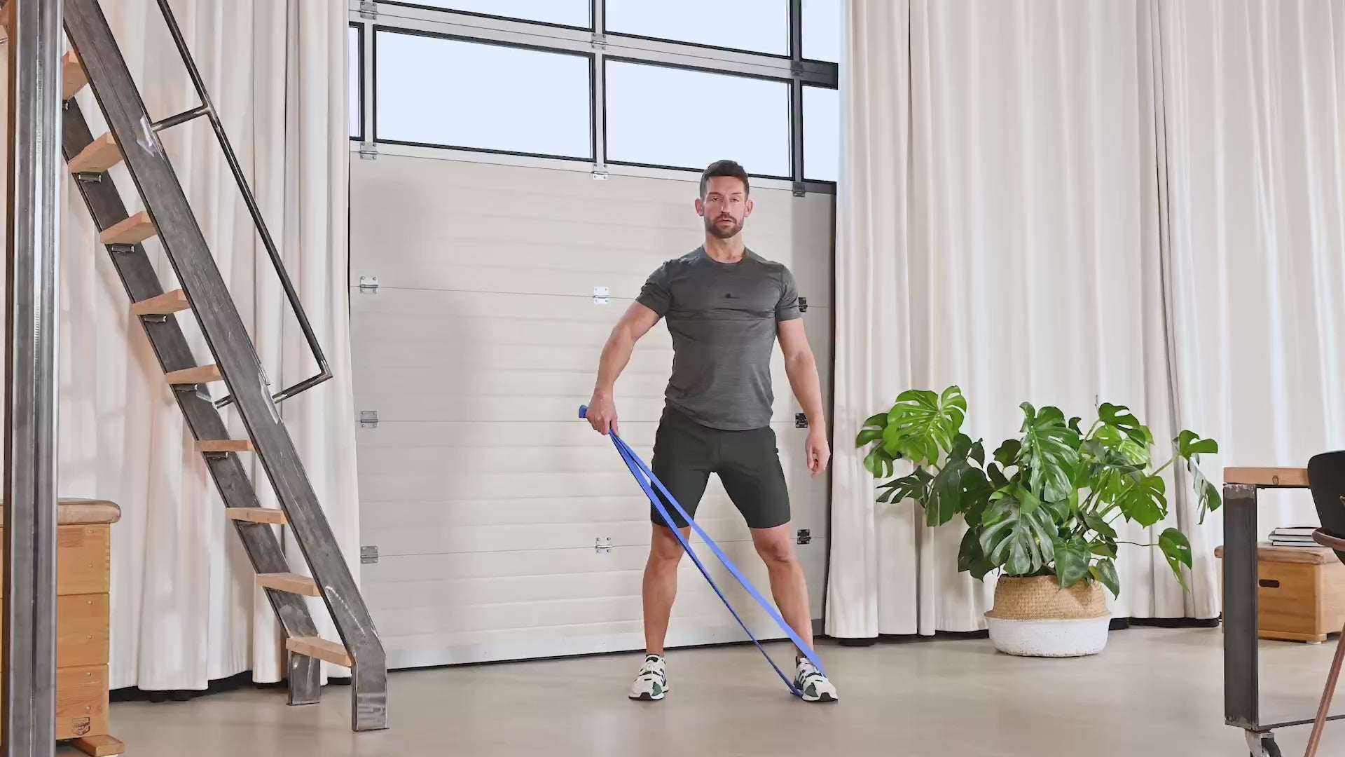 Mann vollführt die Übung Biceps and Abductor Combo mit dem TheraBand.