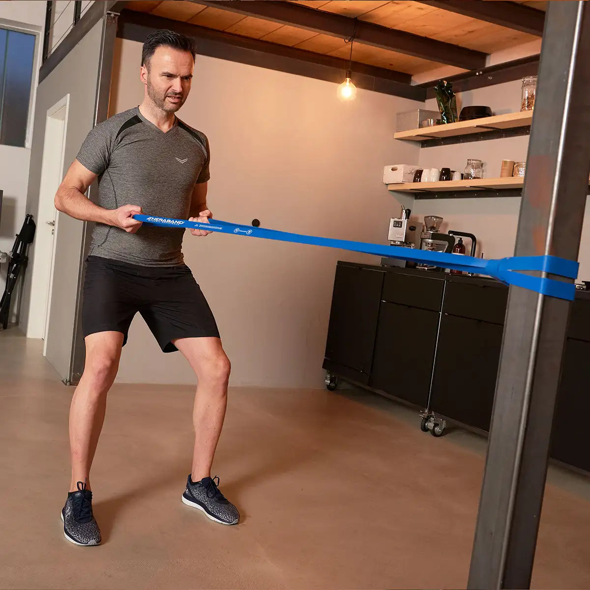 Mann trainiert mit blauem TheraBand High Resistance Band.