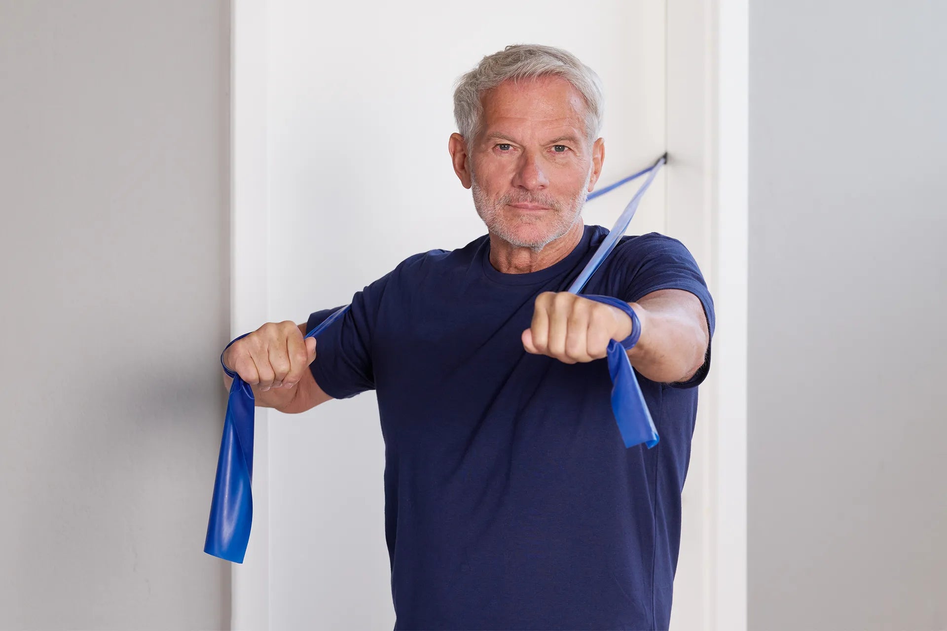 Mann macht eine TheraBand Übung mit einem blauen Fitnessband.