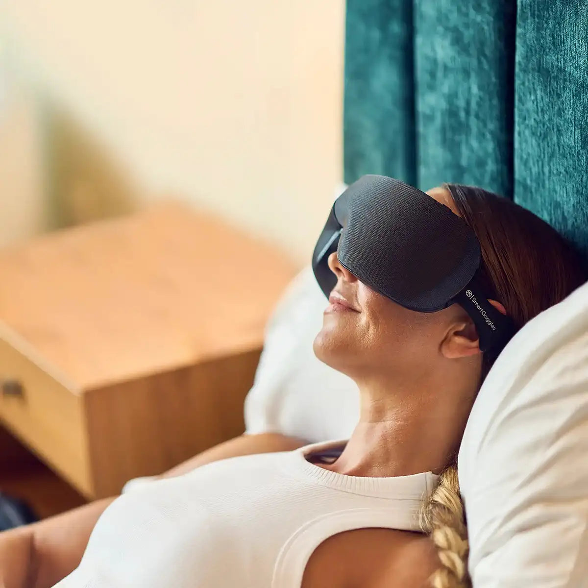 Frau liegt im Bett und trägt ein Therabody SmartGoggles Wearable.